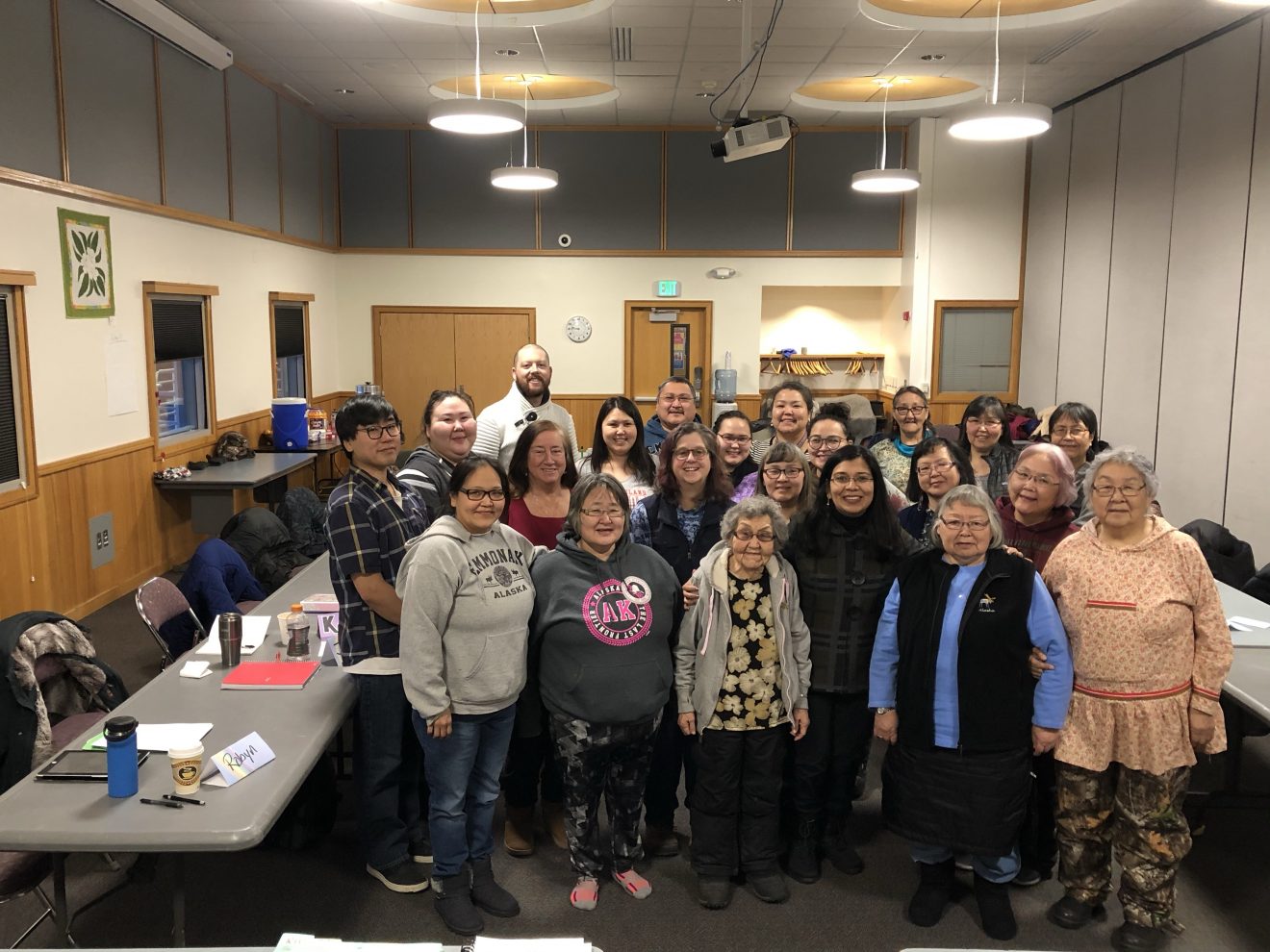 A group of about two dozen people pose for a photo in a conference room.