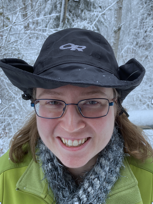 Head shot of a woman wearing winter clothing. The picture is taken outside in the winter.