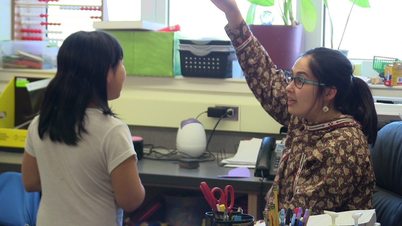 A teacher talks to a young student.