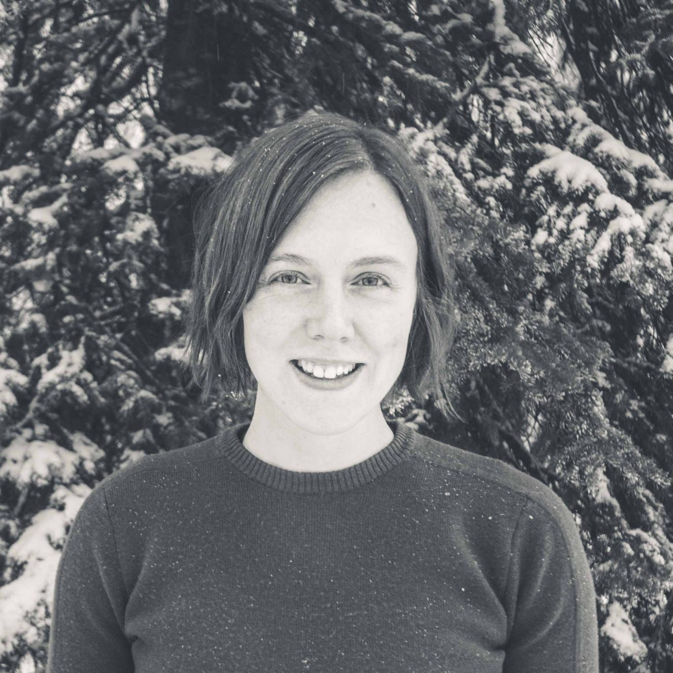 Photo of Erin Trochim standing in front of a snow-covered spruce tree.