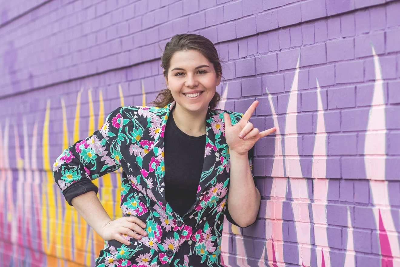Photo of Hayden Kristal leaning against a purple wall.