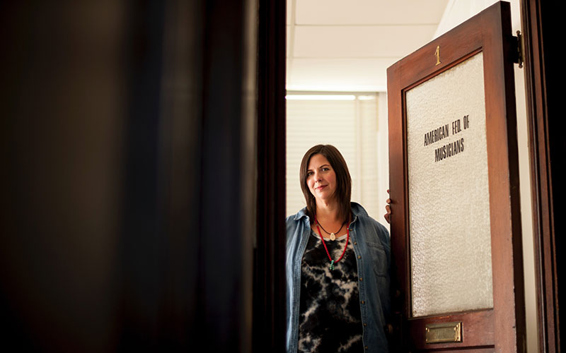 Woman who appears to be a professor standing with her office door open.