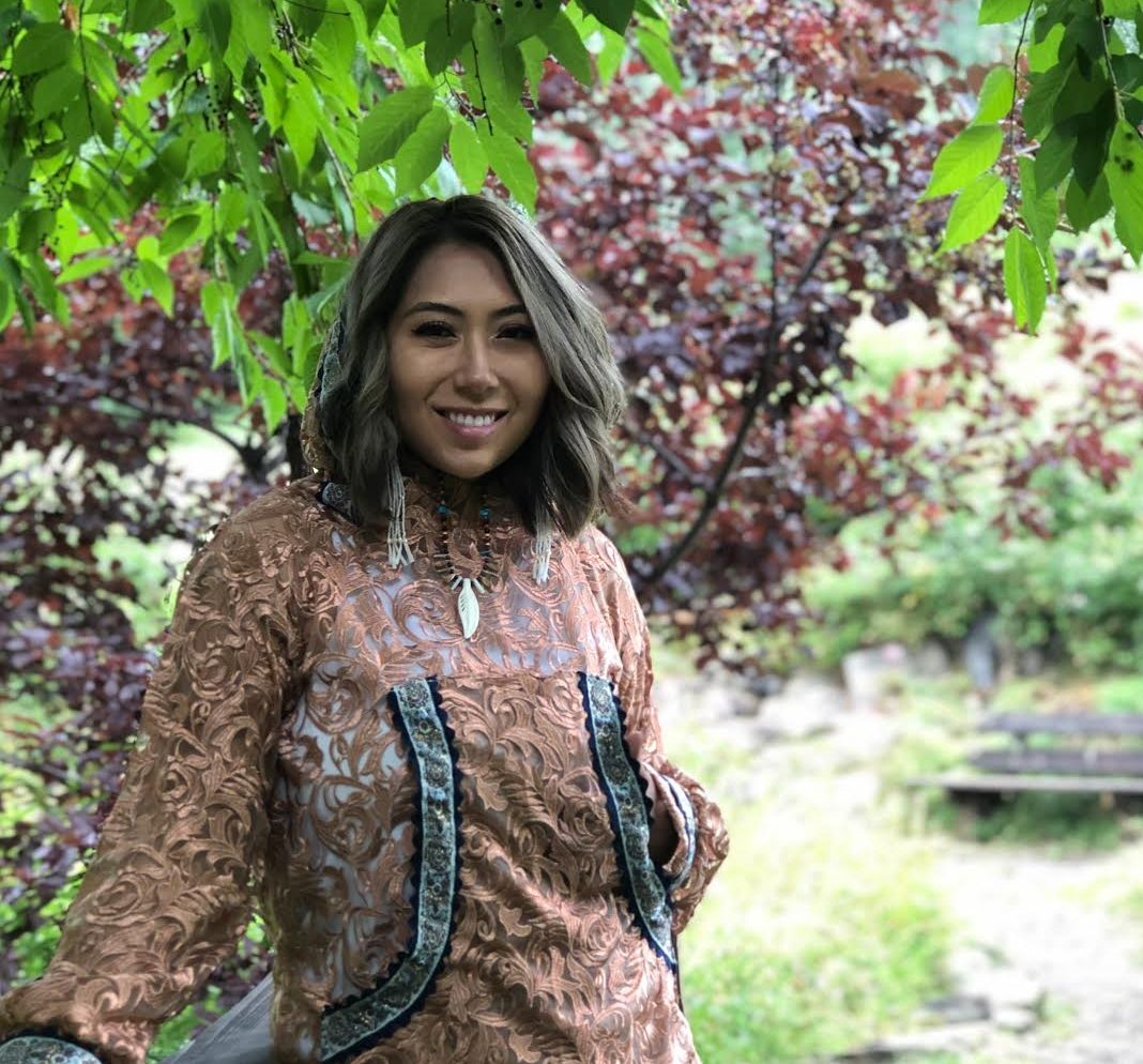 Woman standing under some trees.