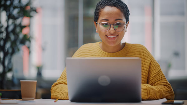 Woman smiling into laptop.