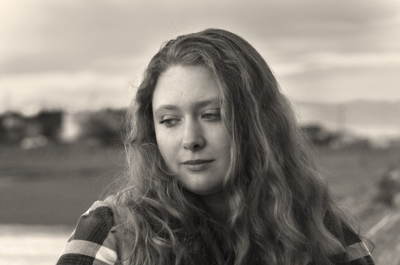 Head shot of Sierra von Hafften. She is wearing a plaid shirt and looking away from the camera.