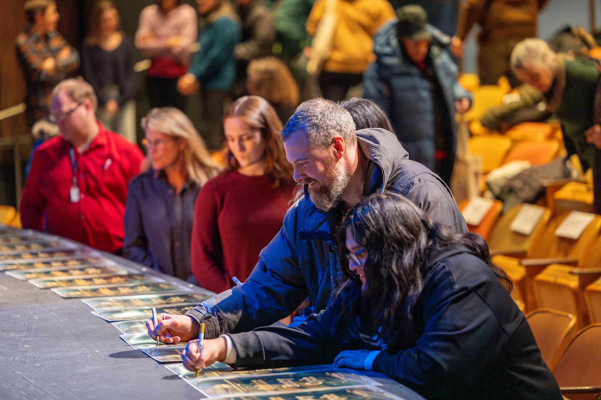 Participants of the 2024 Solstice Poetry Cycle sign commerative posters of the event before the start of the show in the Salisbury Theatre, Jan. 30, 2025. (UAF photo by Leif Van Cise)