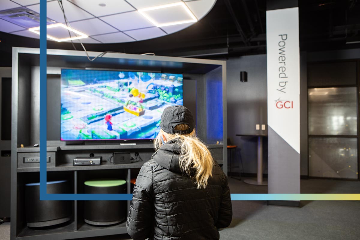 A student plays a console game at one of the TVs in the Esports Center