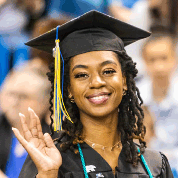 A graduating business student waves during commencement