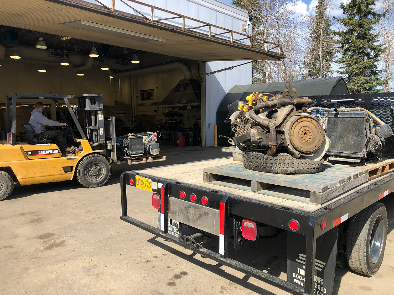 A forklift operator moves donated engines from truck to shop.