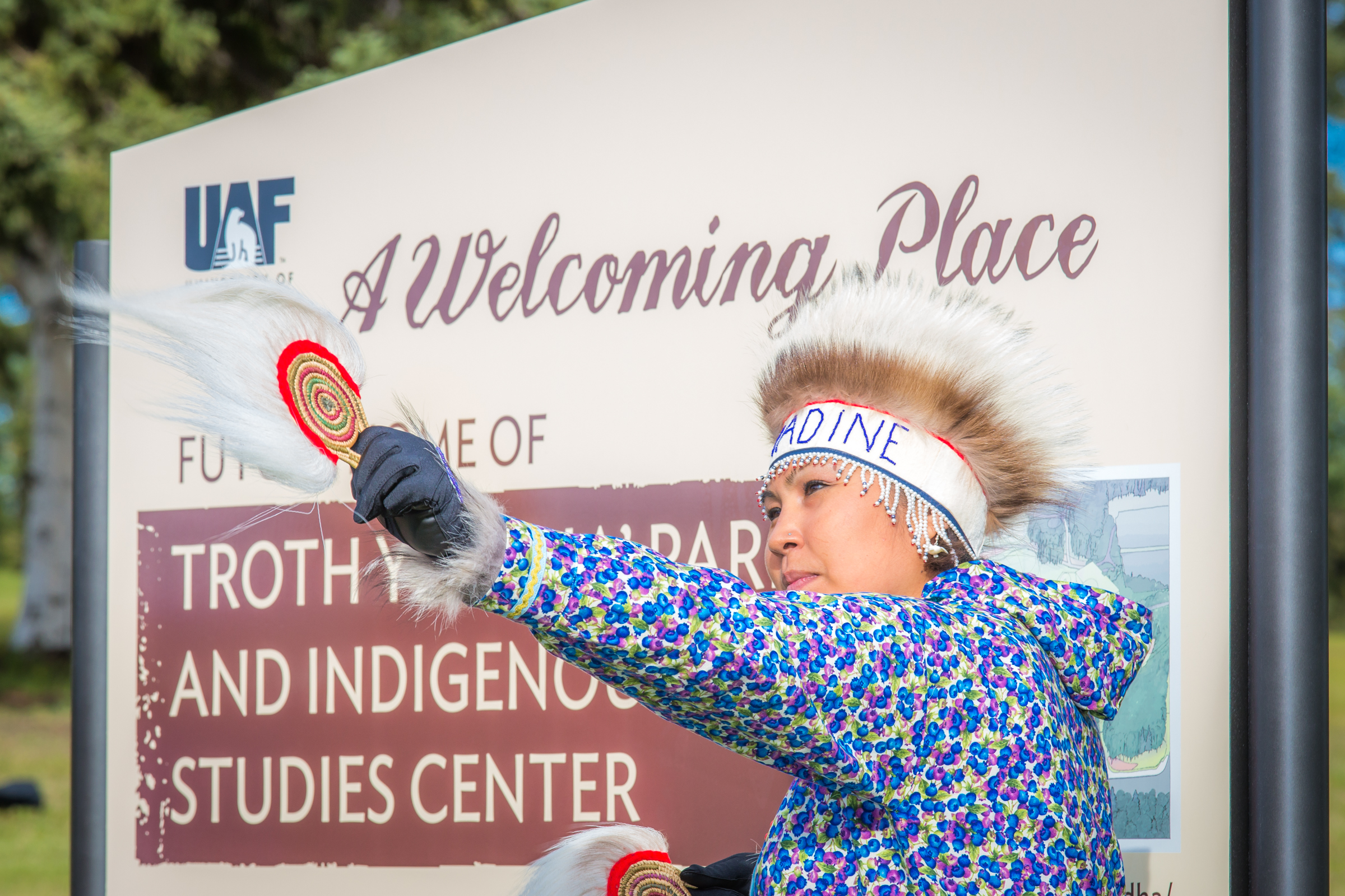 Alaska Native woman dancing near Troth Yeddha' sign