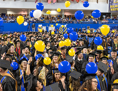 Commencement celebration - students in cap and gown with balloons falling down upon them