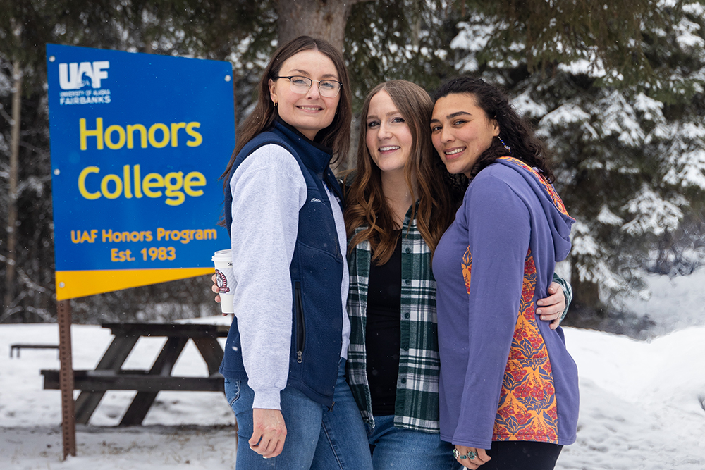 Three students stood by the Honors College sign on Friday April 11, 2025
