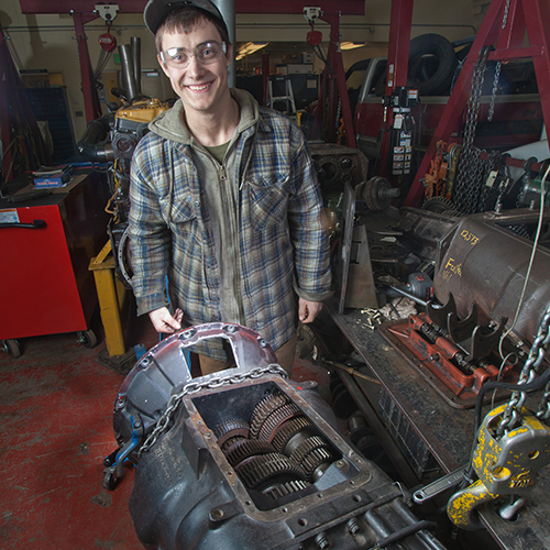 Student standing next to diesel engine