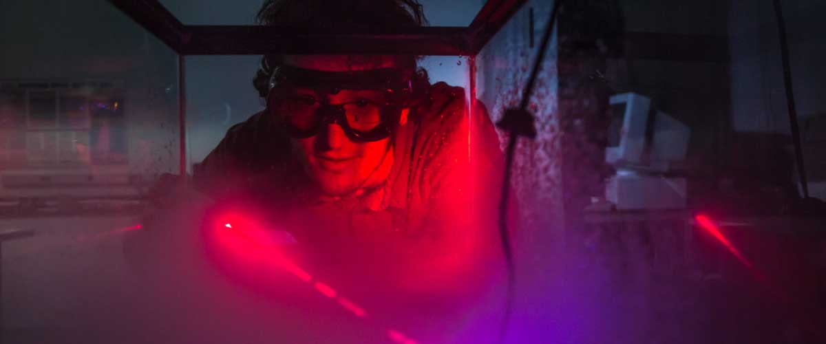 UAF student Michael Succone experiments with light from a laser as its being scattered by clouds of condensation inside an aquarium in a Reichardt Building lab