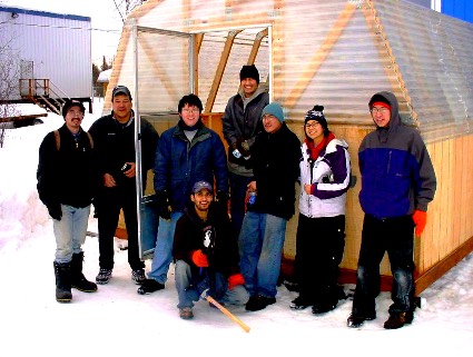 students pose proudly in front of a greenhouse they built together