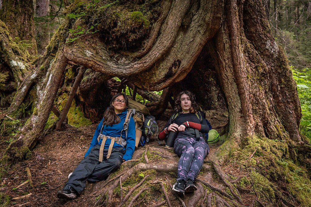4-H youth sitting next to a large tree
