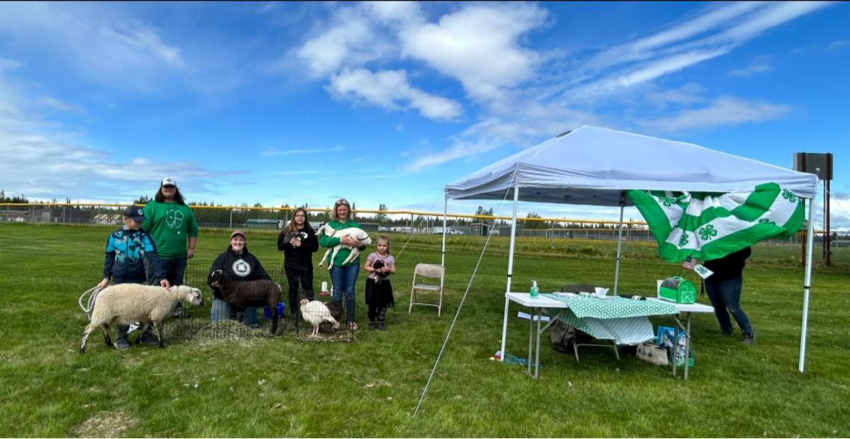 People sitting next to booth in field