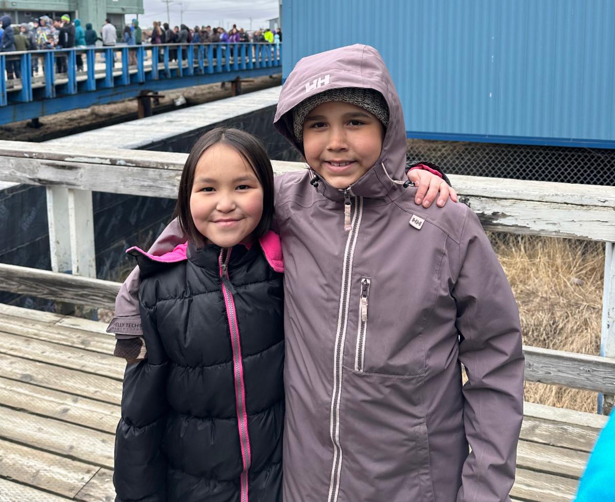 Two youth stand on a bridge, smiling, with another bridge visible in the background