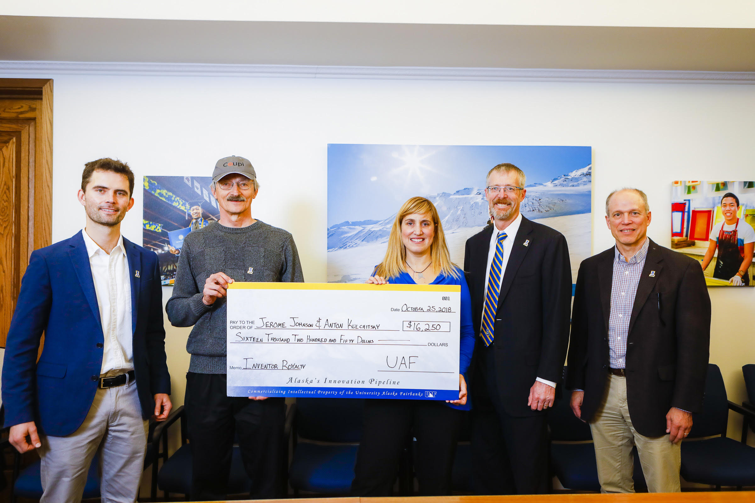 Jerry Johnson receives a check from OIPC’s Gwen Holdmann for the startup’s first share of their revenue. UAF photo by JR Ancheta.