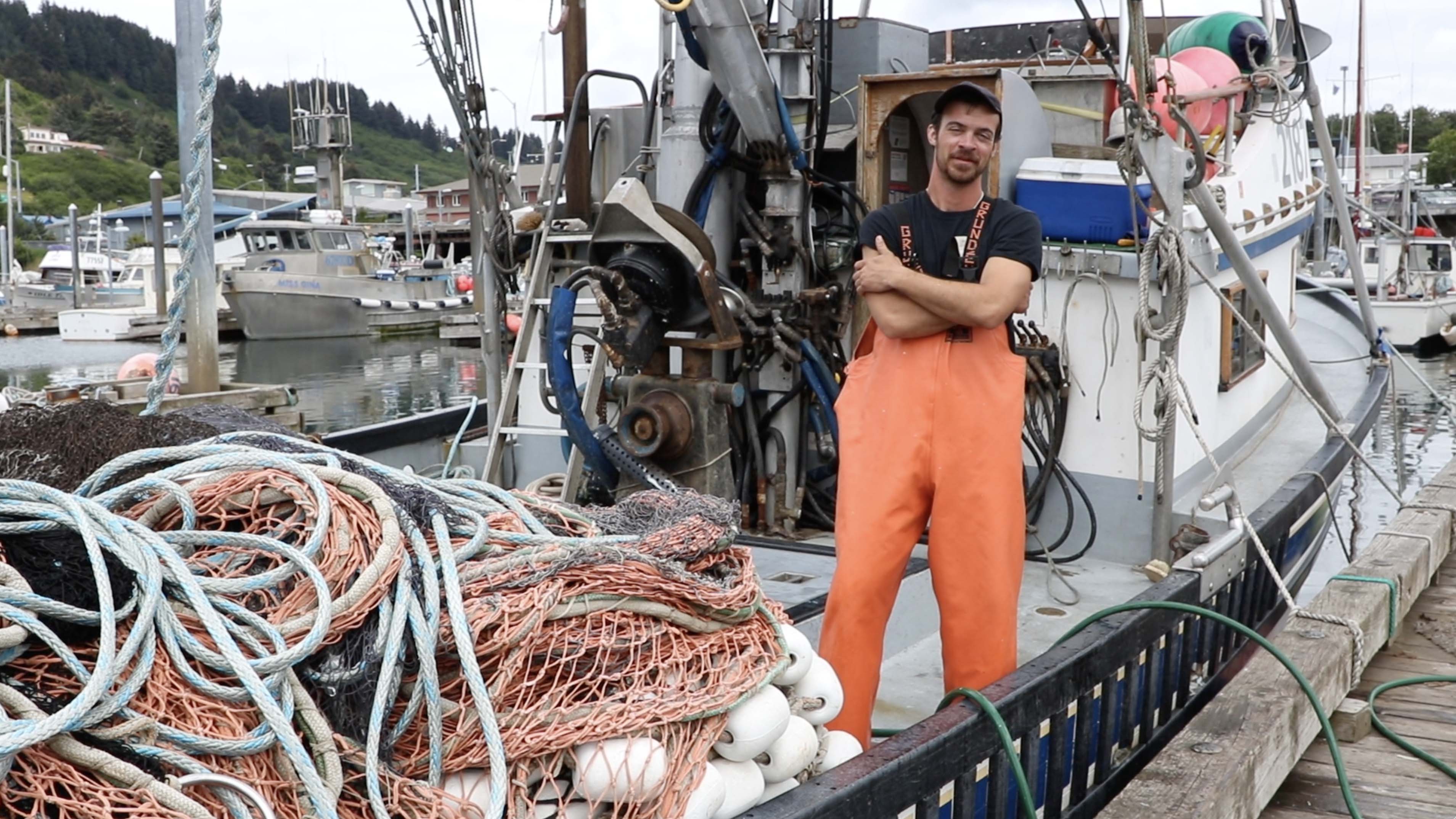A fisherman standing on the deck of a fishing boat in Kodiak Harbor. Photo by Amanda Byrd.