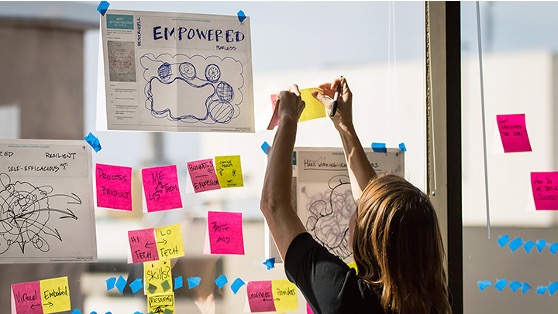 A woman placing post-it notes on a board. Photo from NSF I-Corps.