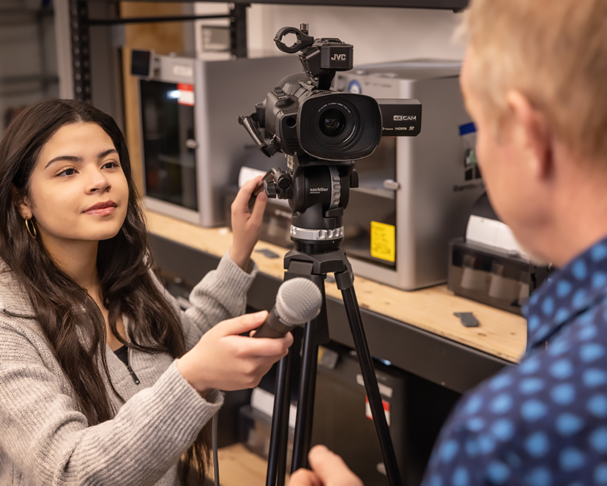 A journalism student holds a microphone to her interviewee. UAF Photo by Charles Mason