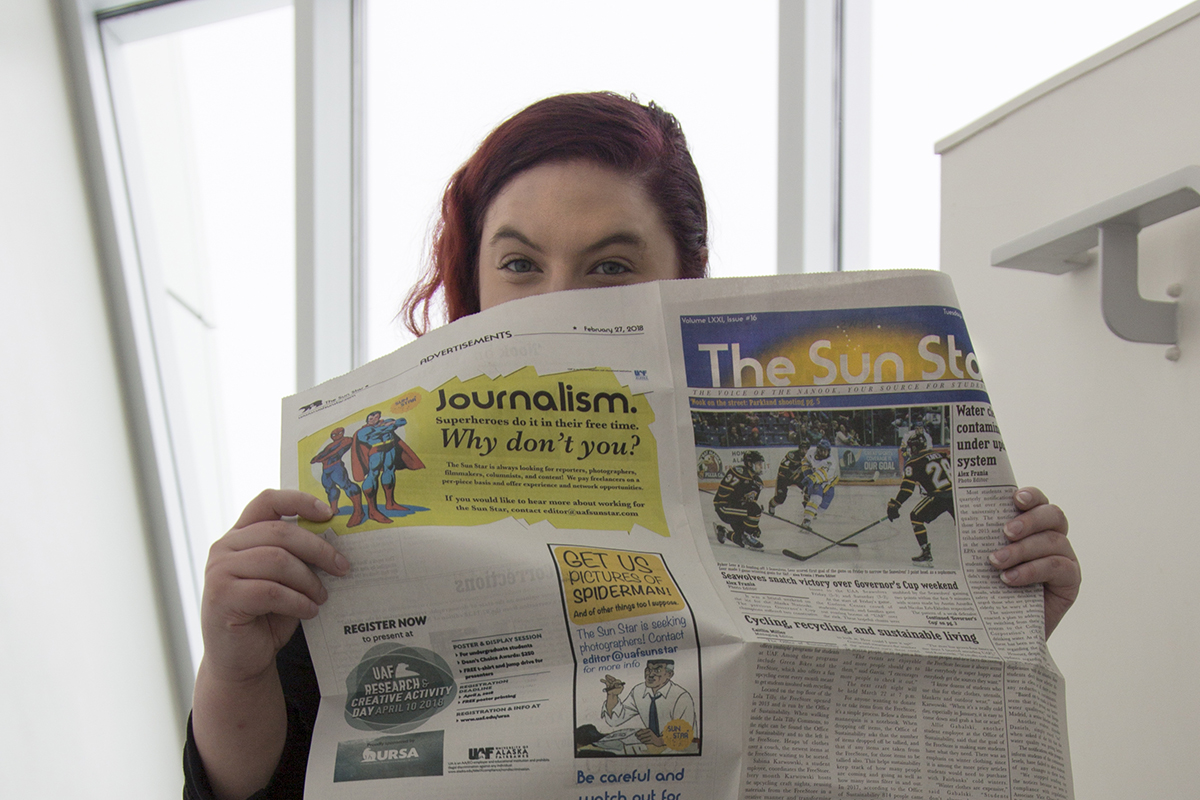 Erin Granger poses in the UA Museum of the North holding a copy of the Sun Star. UAF Photo by Sarah Manriquez