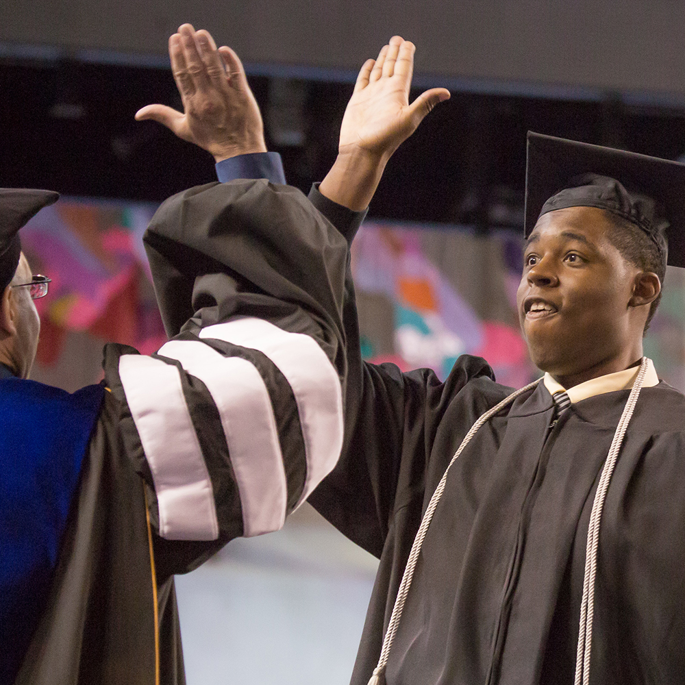 Robert Kinnard III shares a high five with Vice Chancellor Mike Sfraga after earning his degree in justice.