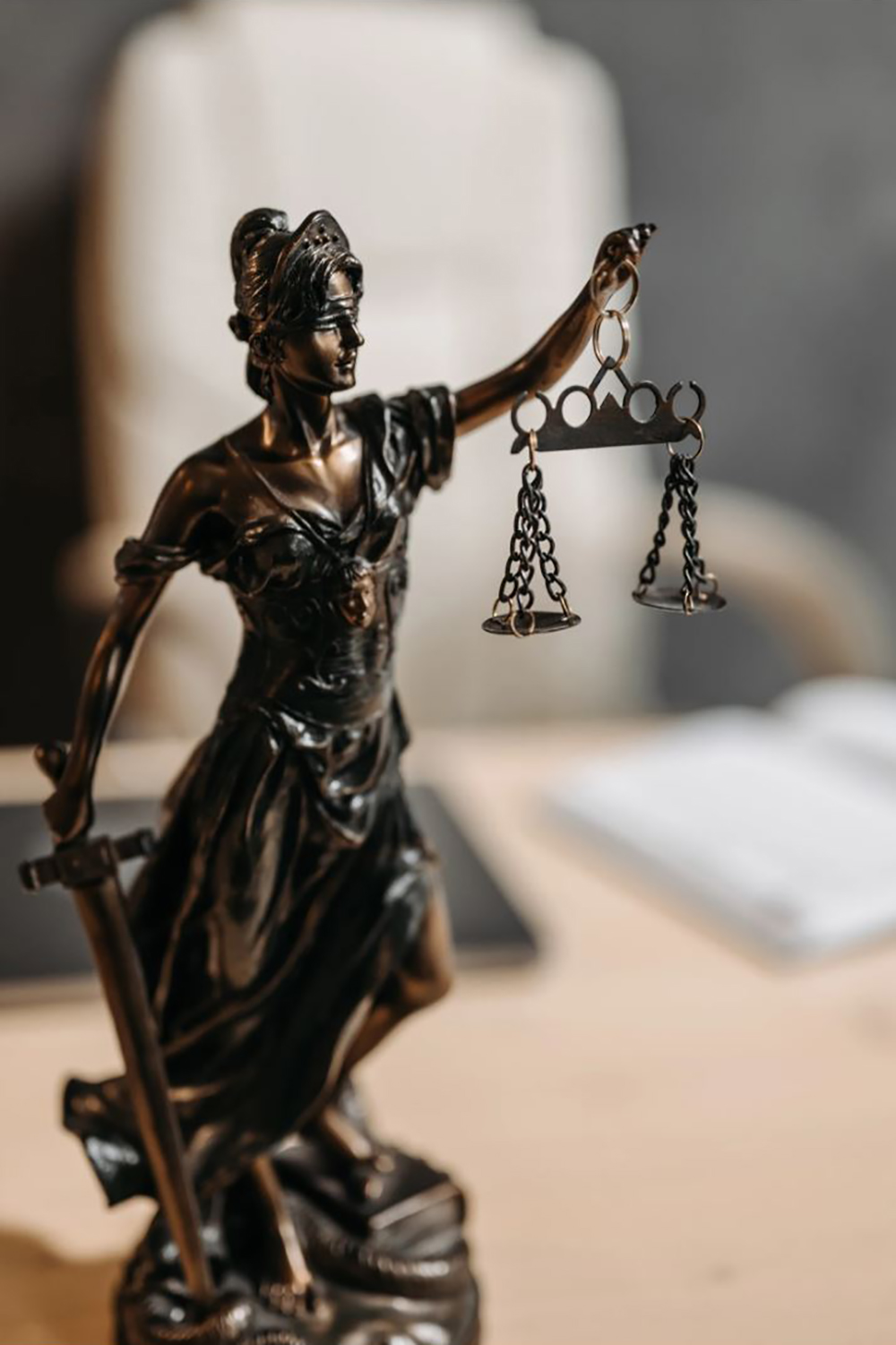 bronze statue of Lady Justice sits on a desk