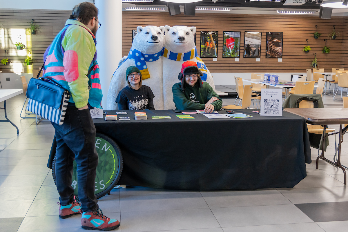 Hosted by Green Bikes, students and employees are encouraged to travel by skiing or biking to and from the UAF campus on March 18, 2026. Iza Lepkowski (middle) and Logan Anderson (right) tabling.