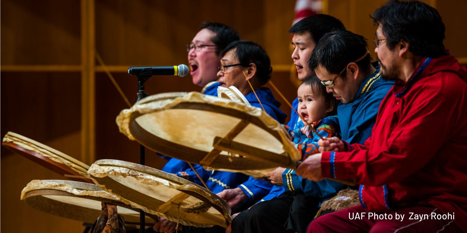 Performers play drums on the stage of the Davis Concert Hall as a part of the Festival of Native Arts.