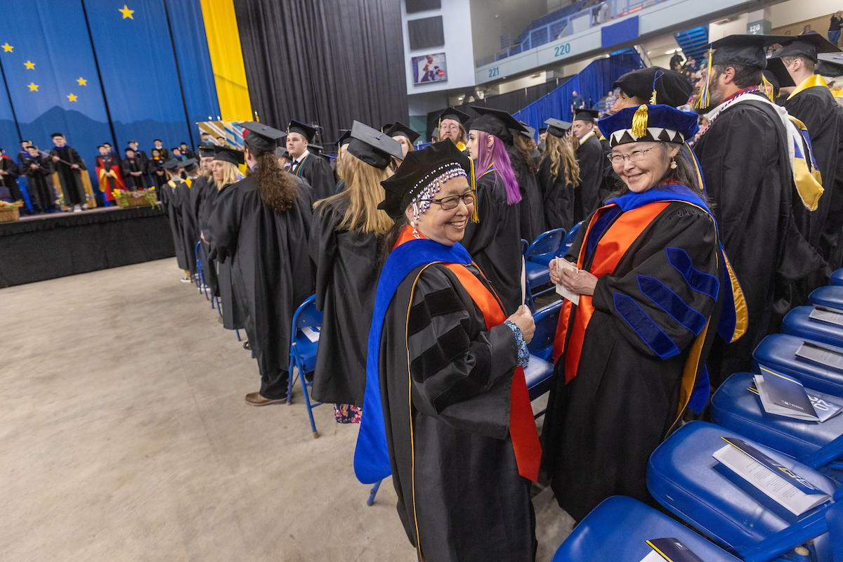 Keggutailnguq Catherine Moses, left, and Angass’aq Sally P. Samson, right, share a laugh during the University of Alaska Fairbanks 2023 Commencement Ceremony at the Carlson Center Saturday, May 6, 2023. Moses, from Kotlik/Toksook Bay, received her Ph.D. in Linguistics: Interdisciplinary Studies. She received her B.A. in 1984, and her M.A. in Linguistics in 2010, both from UAF. Samson, from Nunapitchuk/Bethel, also received her Ph.D. in Linguistics: Interdisciplinary Studies. She received her B.A. in 1998, and her M.A. in Linguistics, in 2010, both from UAF. | UAF Photo by Eric Engman