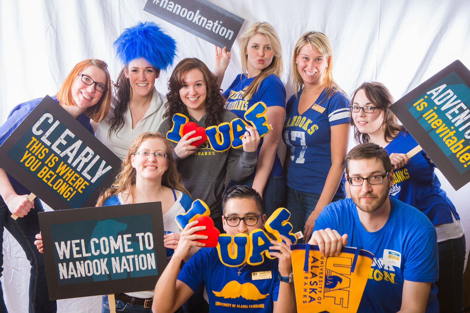 Orientation leaders pose in their UAF gear holding props and signs welcoming new students