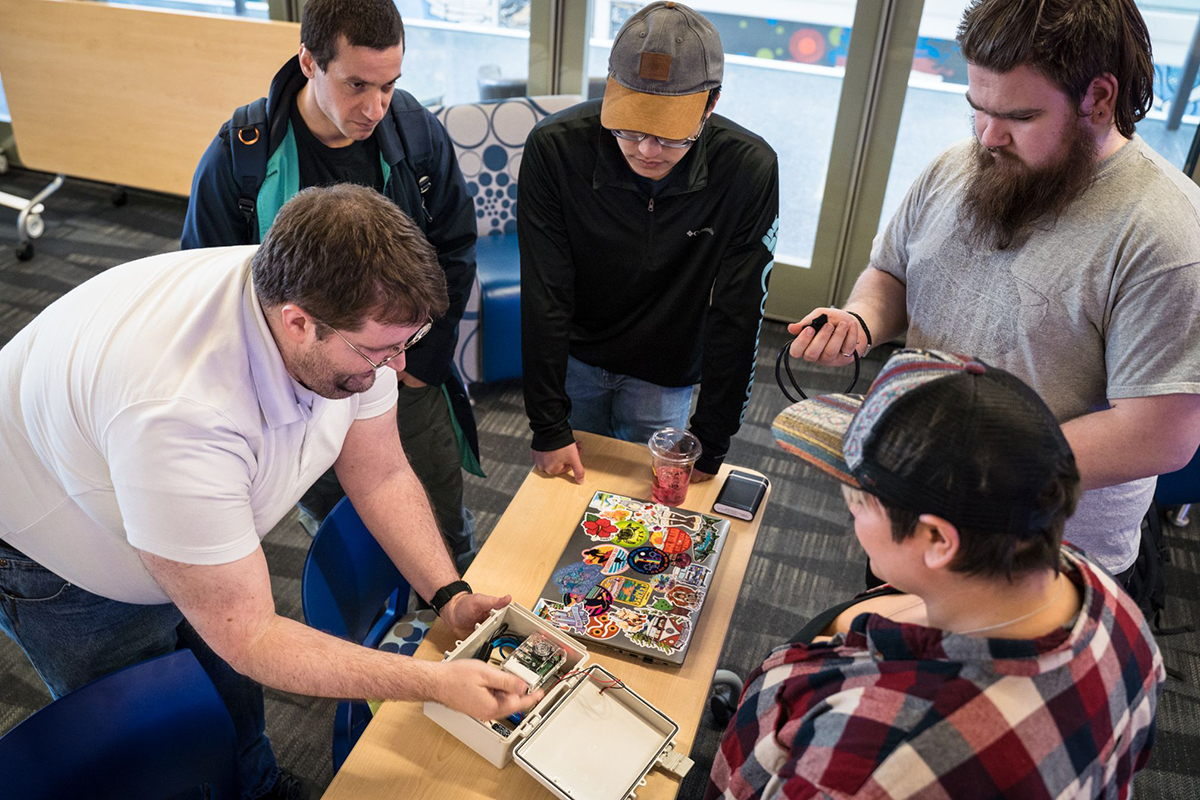 Five students around a table working on a project