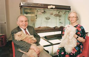 Photo of Vogels holding cats, seated in front of a fish tank