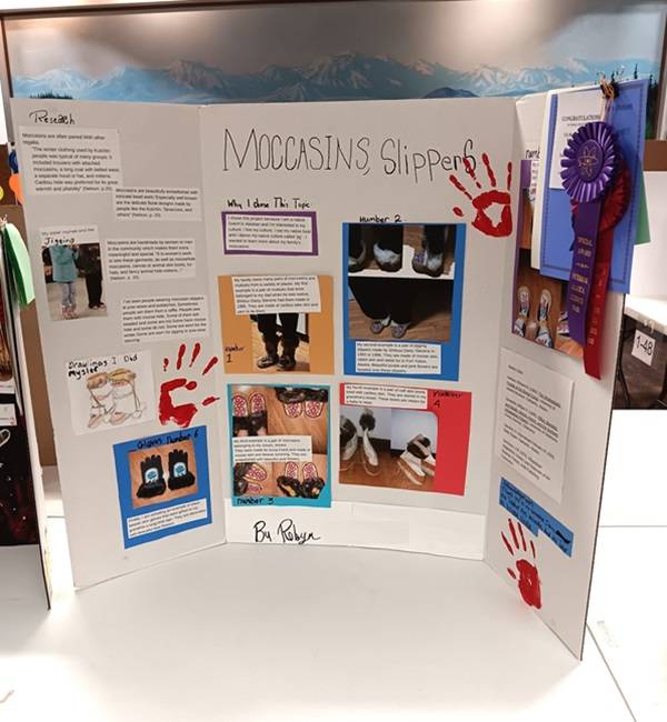 Science Fair posterboard with the title "Moccasins, Slippers" and several photos of beaded moccasins.