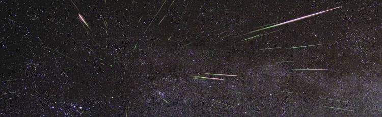 View of the night sky with several meteors streaking through it.