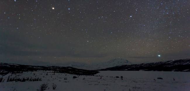 Starry night sky over a winter landscape.