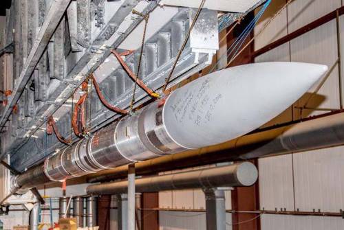 A rocket laying on its side being assembled in a warehouse at Poker Flat.