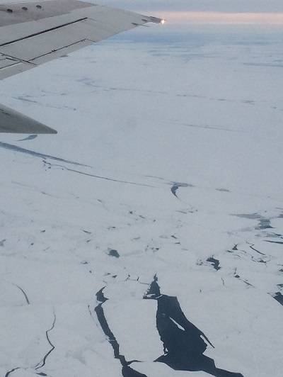View of sea ice from above. An airplane wing is visible in the upper left.