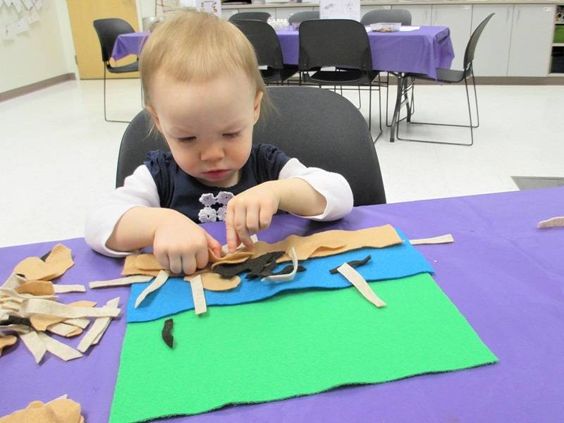Child arranging felt pieces to form the shape of a beaver lodge.