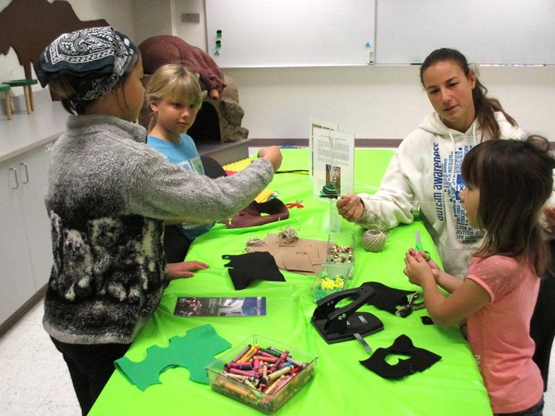 Group of children and adults at a table with craft supplies.