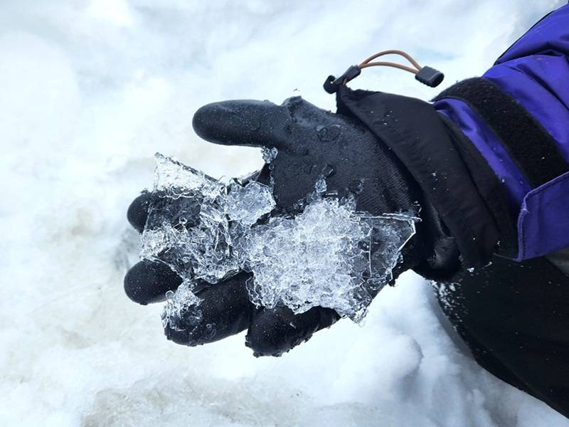 Close up of a hand holding a piece of ice.
