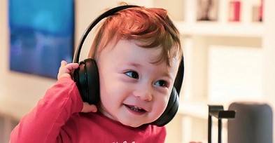 A young child wearing a pair of black headphones and smiling.