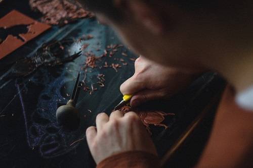 Close-up of hands carving a linocut print.