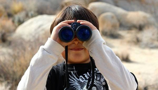 A child holds binoculars to their eyes.