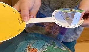 Child's hands holding a Arctic Seasons model next to a globe.