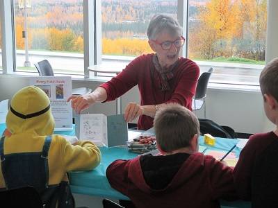 A volunteer explains an activity to children at Berries Family Day.