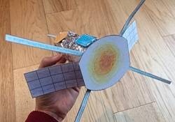 Hand holding a model solar probe made of a toilet paper tube, paper, and cardboard.