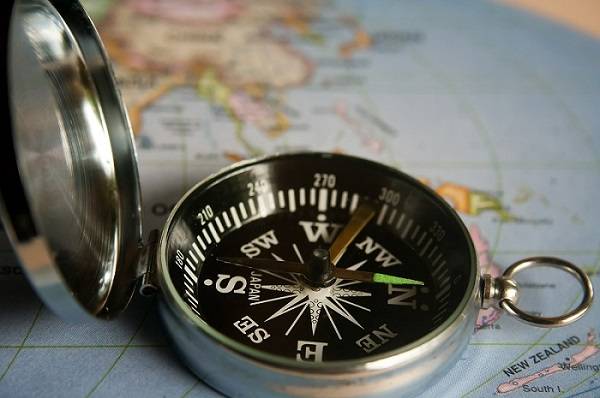 Close-up of a compass sitting on top of a world map.